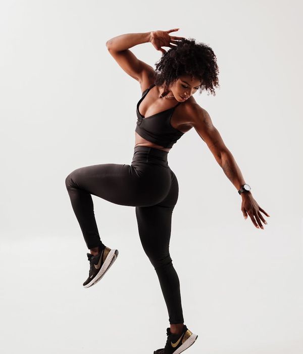 Energetic woman in sportswear performing a dynamic cardio movement in a modern studio.